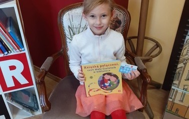 Dziewczynka z książką w bibliotece