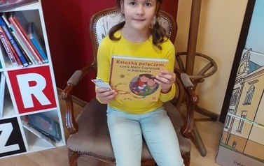 Dziewczynka z książką w bibliotece