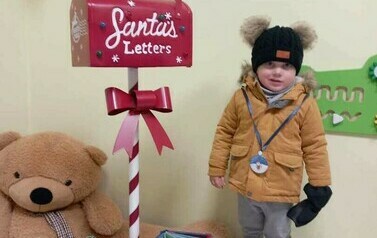 Chłopczyk wkłada list do Mikołaja do skrzynki Mikołajkowej.