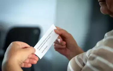 cytat na kawałku papieru. Papier trzymany przez kobietę.