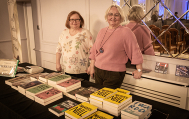 Dwie kobiety stojące przed stoiskiem z książkami.